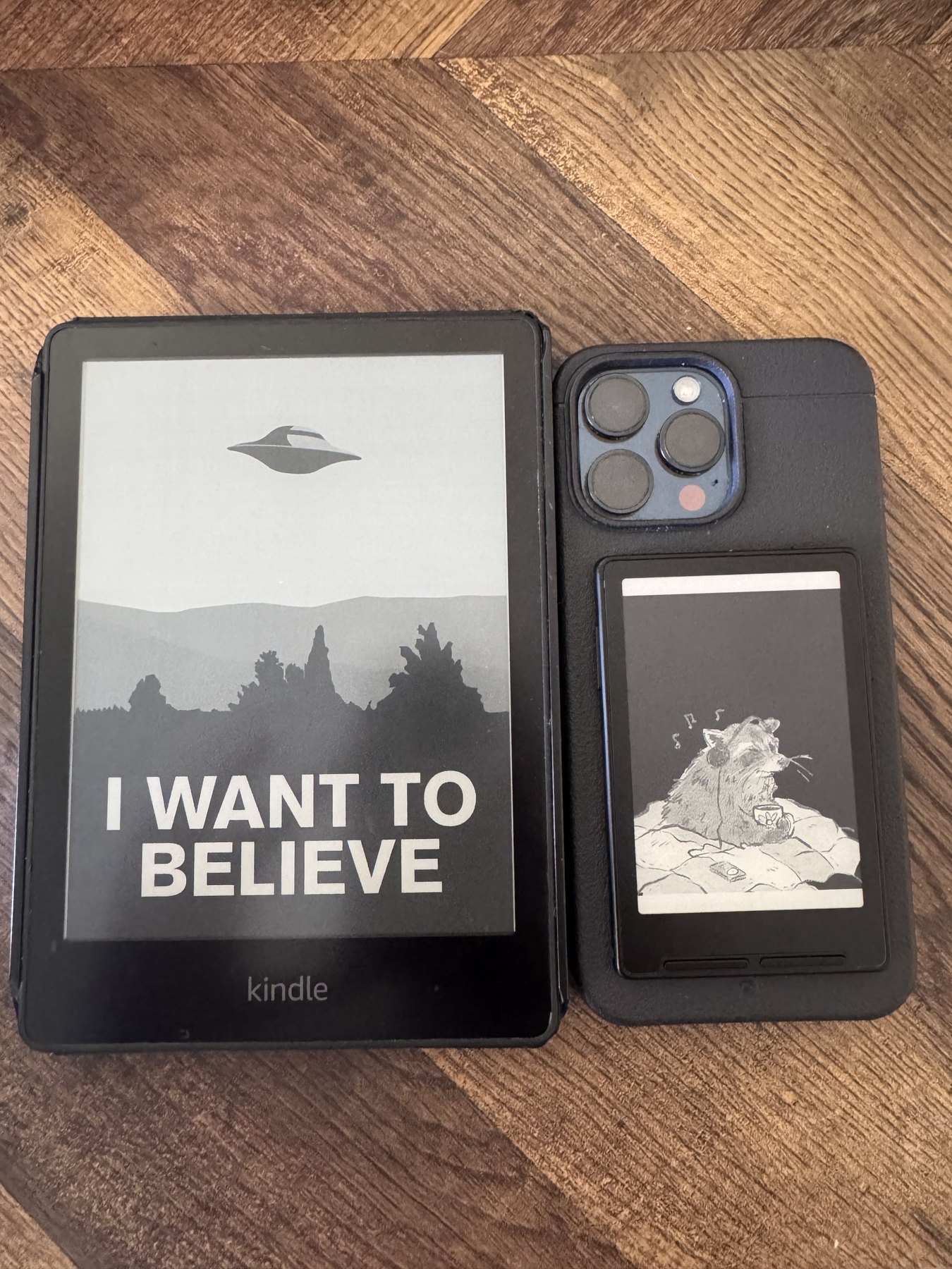 A Kindle and a phone-mounted Xteink e-reader displaying custom black-and-white screensavers side by side